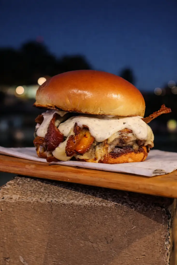 Hambúrguer com bacon e molho branco ao entardecer